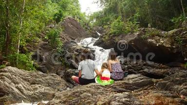 一家人爸爸妈妈女儿坐着欣赏瀑布美景